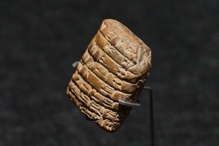 A cuneiform clay tablet on display, mounted against a dark background